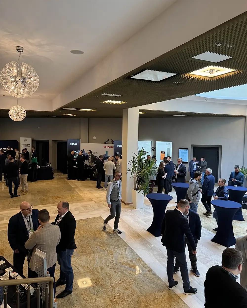 Attendees talking around high tables and exhibitor stands in the venue foyer during KNX Experts Meeting 2024