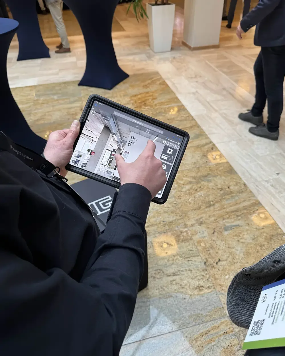 Person using a 3D digital twin view on a tablet in the venue foyer at KNX Experts Meeting 2024