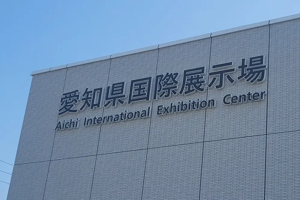 Facade sign of the Aichi International Exhibition Center in Japanese and English against a blue sky