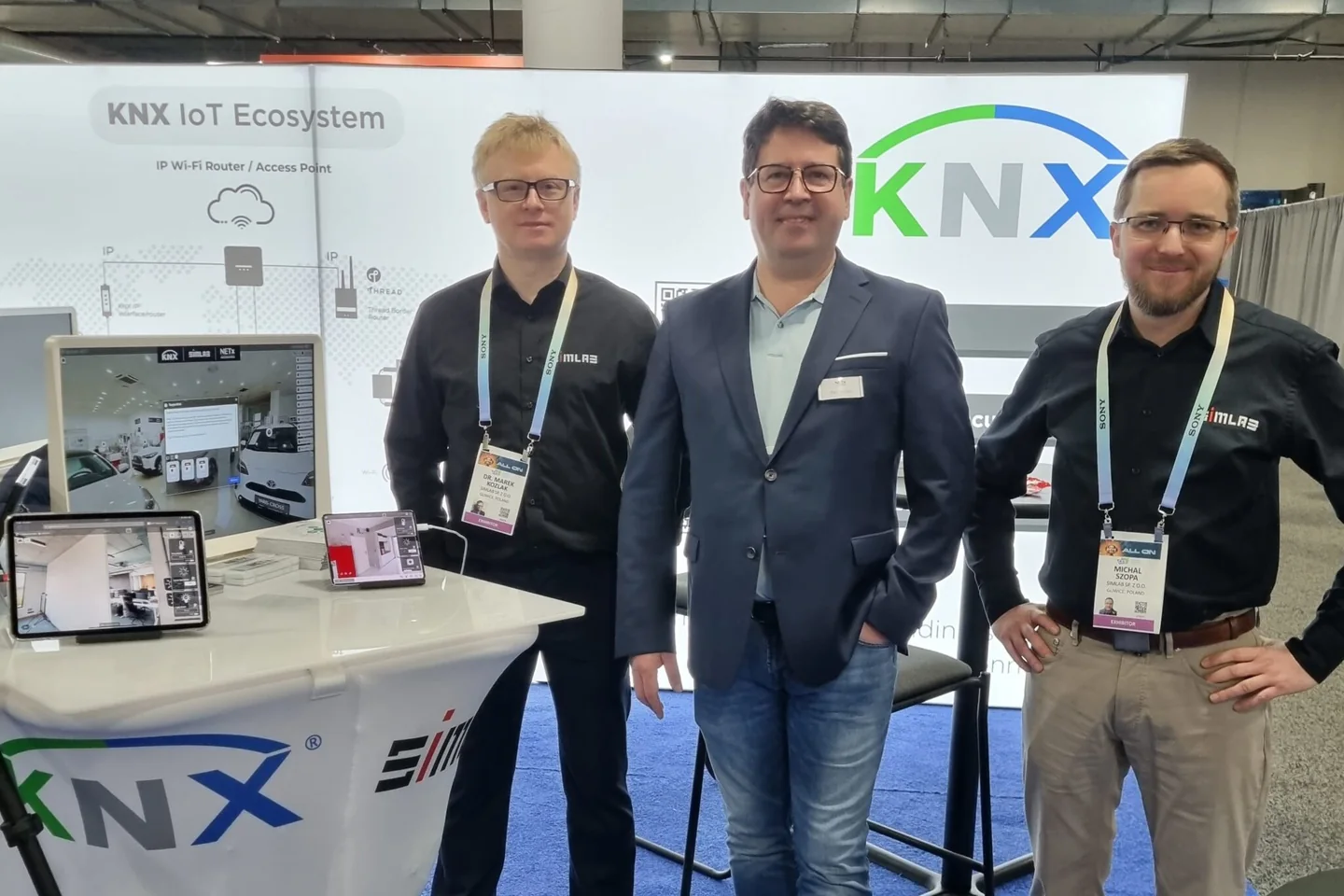 Marek Kozlak and Michał Szopa of SIMLAB with Paul Furtak of NETx Automation at the KNX IoT Ecosystem booth, SIM-ON demos running on a monitor and tablets