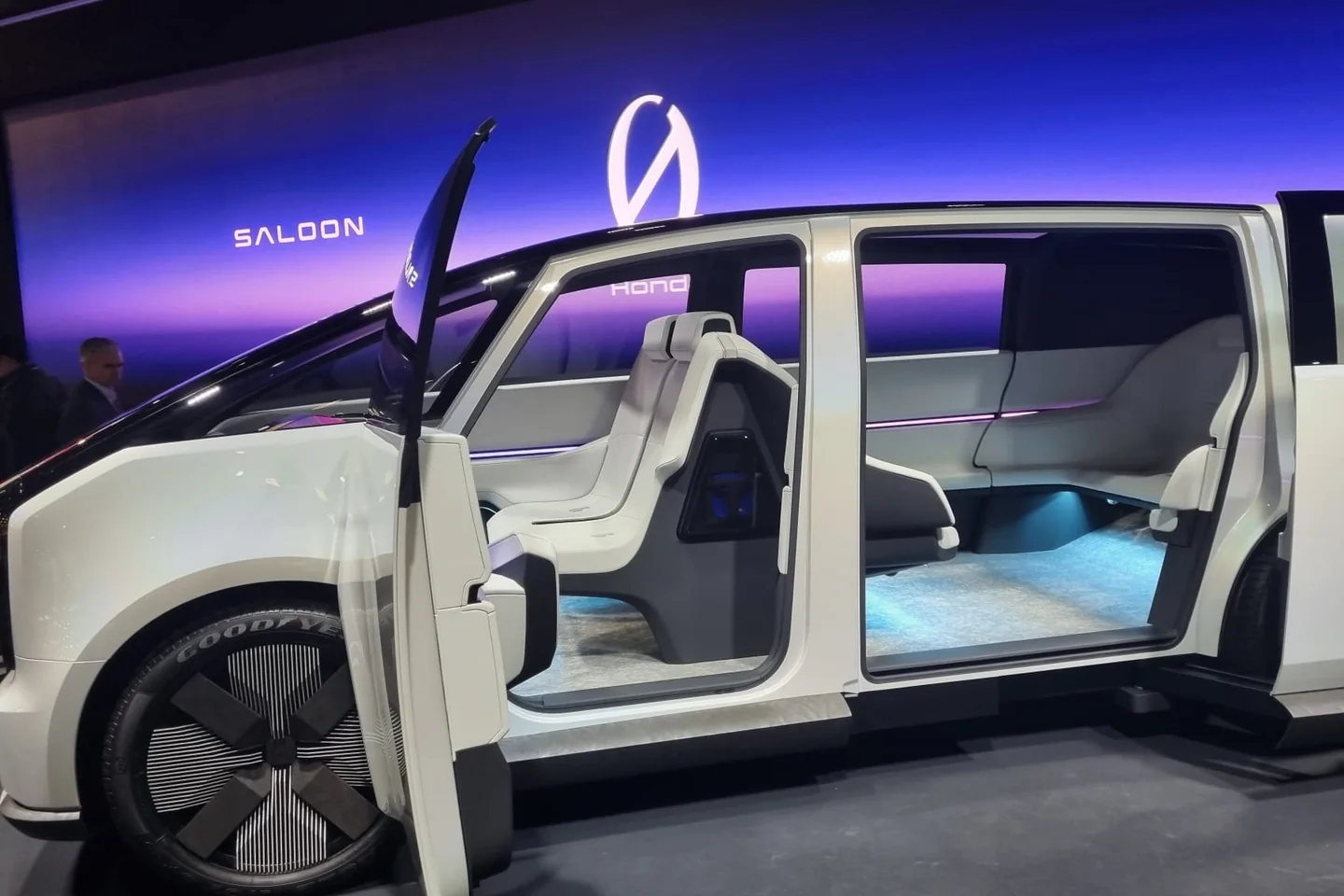 Honda Saloon concept car with its doors open, showing a white lounge-style interior, on the CES show floor