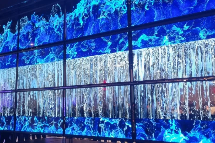 Large wall of display panels showing blue water and waterfall visuals at CES