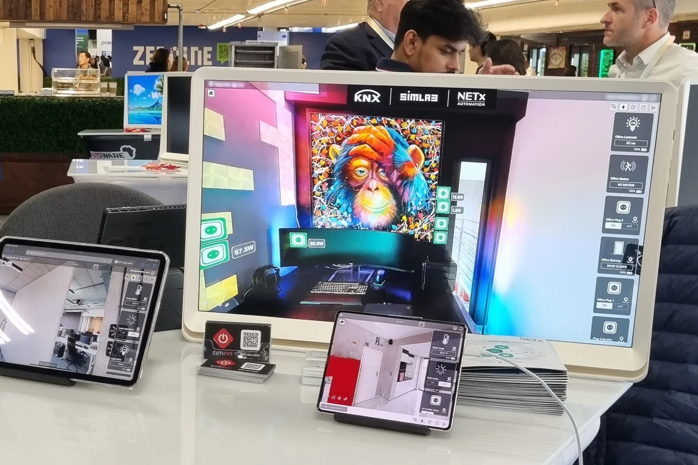SIM-ON demo at CES: monitor with a 3D office digital twin, KNX, SIMLAB and NETx Automation logos and IoT control panels, plus two tablets running SIM-ON