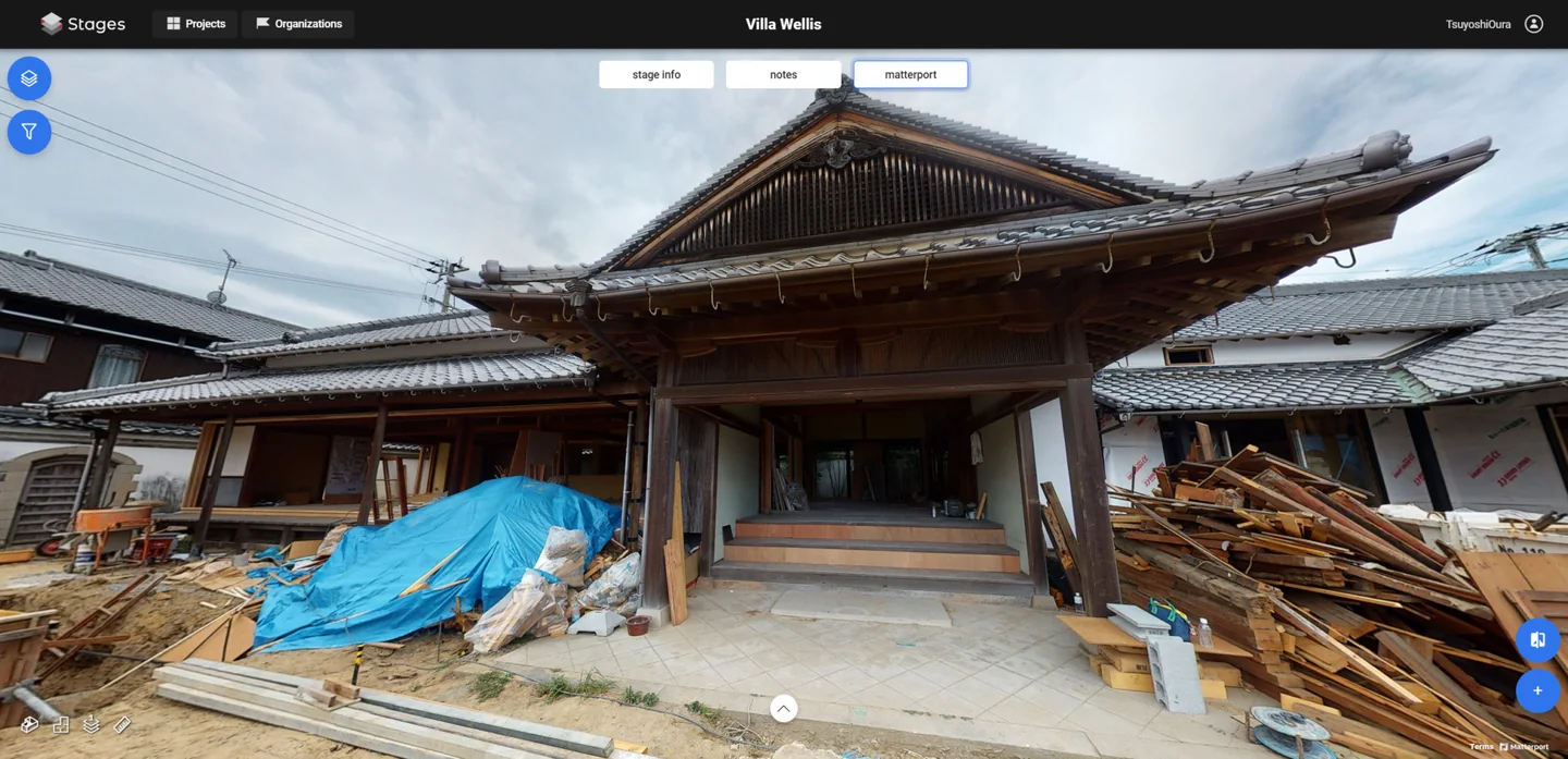 STAGES view of Villa Wellis during renovation: entrance of a traditional Japanese house with tiled roofs, stacked timber and a blue tarp