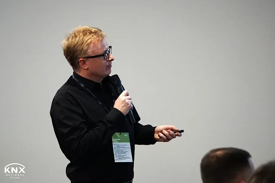 SIMLAB CEO Marek Kozlak presenting with a microphone and a remote at KNX Experts Meeting 2023