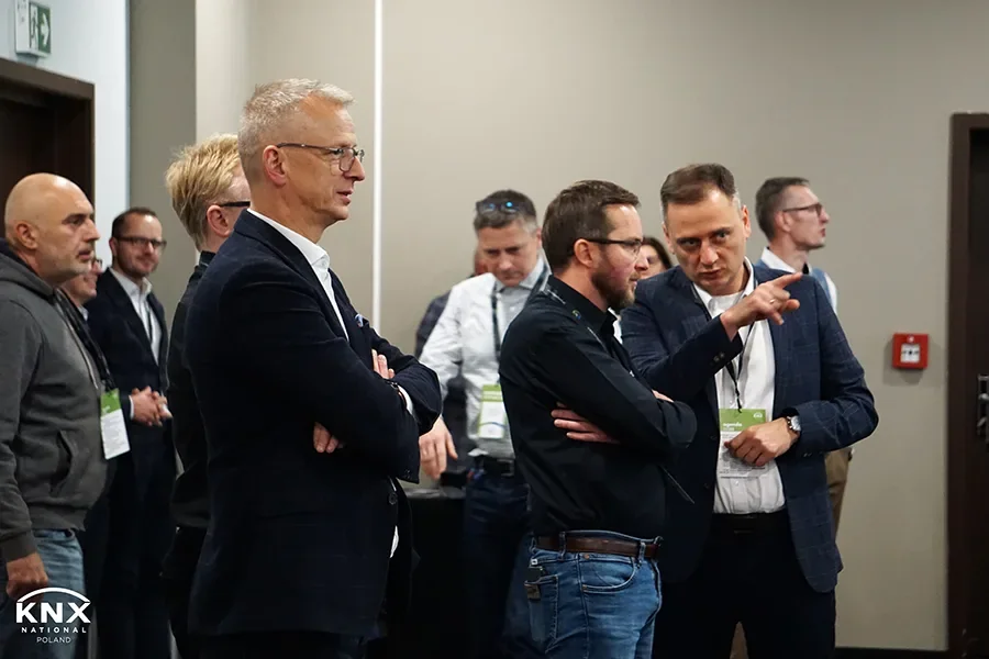 Attendees with conference badges standing and talking at KNX Experts Meeting 2023, among them SIM-ON Product Owner Michał Szopa