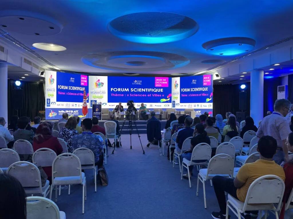 MEDIBAT 2023 Forum Scientifique: a panel on stage under screens announcing the theme Sciences et Villes on 5 October 2023, with the audience seated in rows