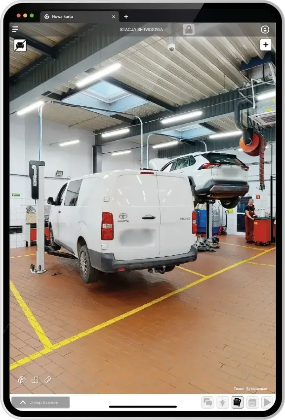 Tablet showing the SIM-ON 3D scan of the dealership service station, with a white Toyota van in a work bay and an SUV raised on a lift