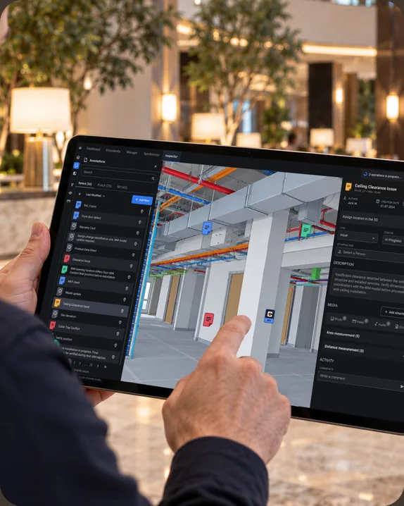 Building owner in a lobby reviewing a 3D building model with annotation markers on a tablet